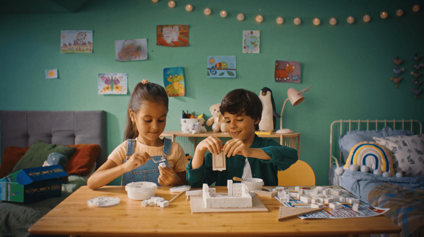 Colorful children's room with two kids building a model with foam blocks and creative toys.