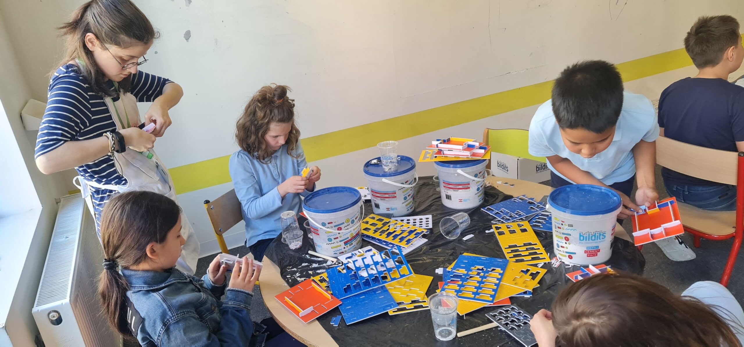 Colorful kids building and playing with construction kits at a table.