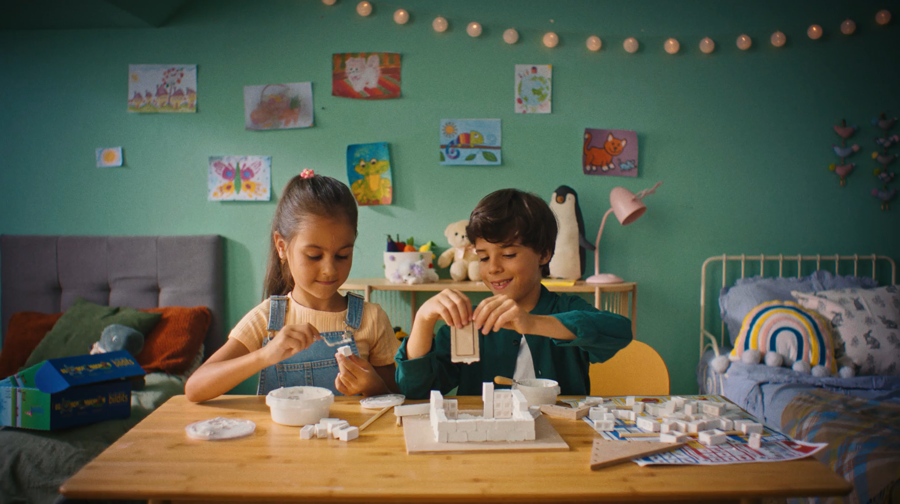 Colorful children's room with two kids building a model with foam blocks and creative toys.